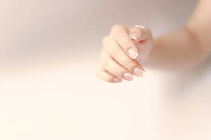 Unhas curtas em tom nude com anel dourado