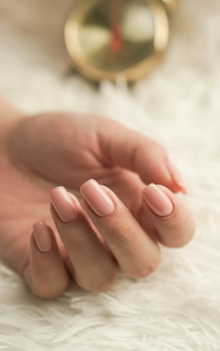 Unhas rosa claro em mão apoiada